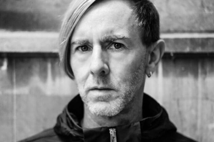 A black and white photo of a man with long hair, featuring Techno Legend Richie Hawtin.