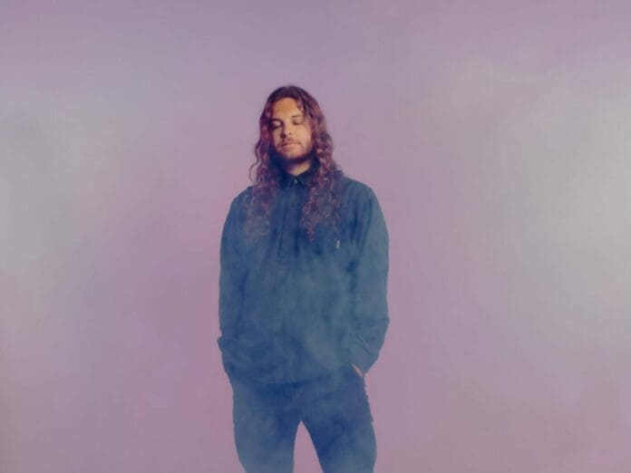 A man with long hair standing in front of a purple background releases 'BODY' EP from forthcoming debut album.