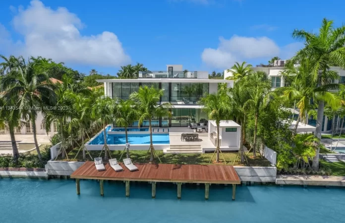 A luxury waterfront home with palm trees and a dock.