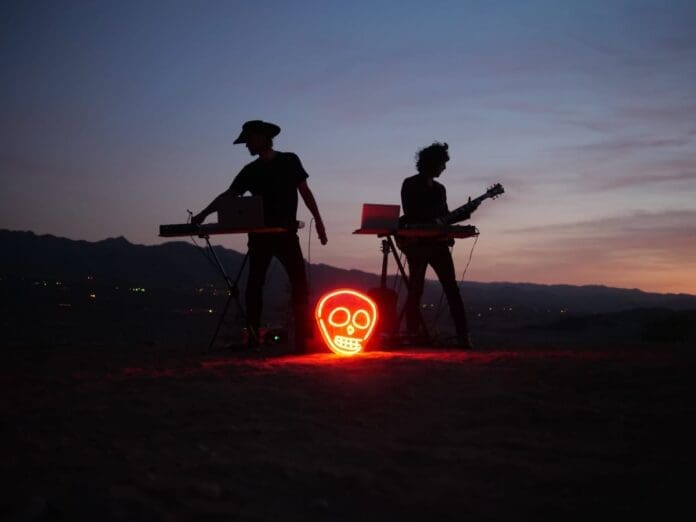 Two people standing in the desert with a glowing skull.