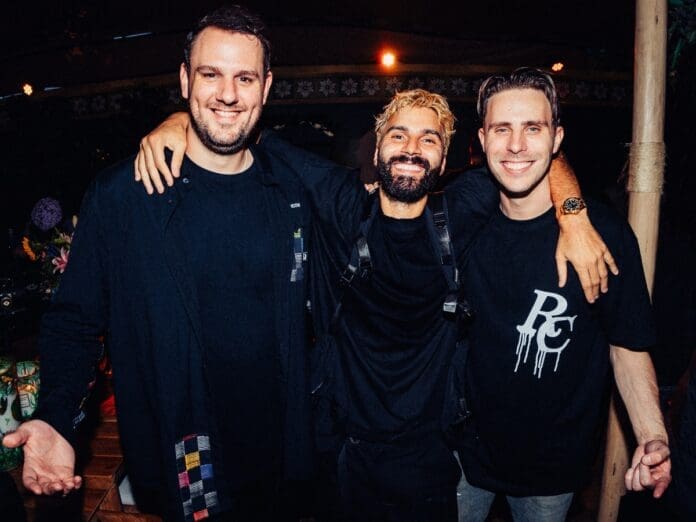 Three men posing for a photo at a party featuring R3HAB and W&W.