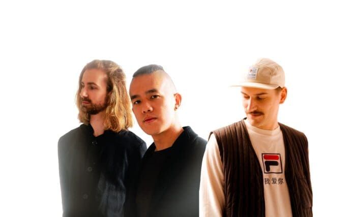 Three men standing next to each other in front of a white background.