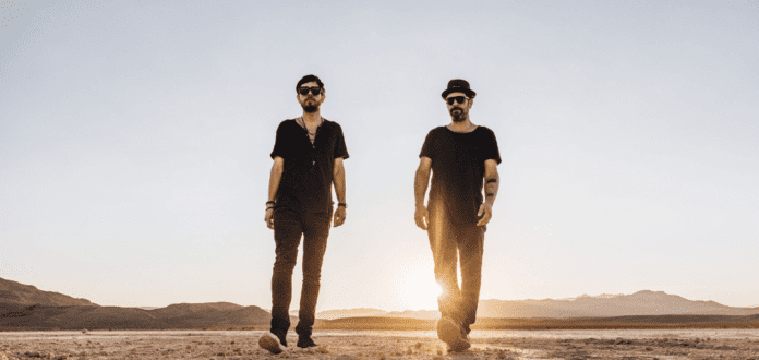 Two Bedouin men standing in the desert at sunset releasing remixes from 'Temple of Dreams'.