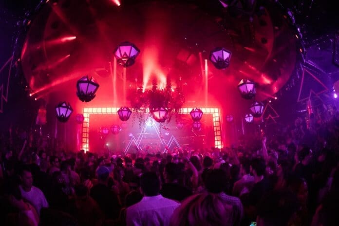 A nightclub crowd with red lights during the Fall 2023 Art of the Wild talent lineup.