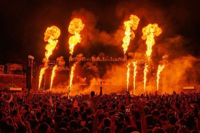 A crowd at a concert with flames, featuring The Chainsmokers.