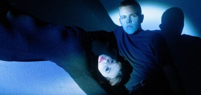 Lucky Iris unveils highly anticipated EP artwork featuring a man and woman posing in front of a blue light.