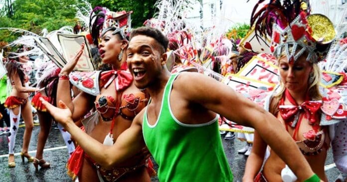 A man in a green shirt is dancing at Notting Hill Carnival this weekend.