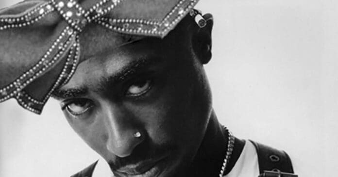 A black and white photo of a man wearing a tupac headband who was arrested in connection with the murder of Tupac Shakur in 1996.