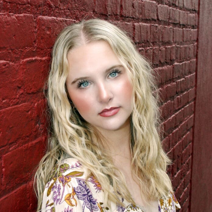 Annah Marcelle leaning against a brick wall.