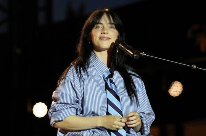 A woman in a blue shirt singing into a microphone.