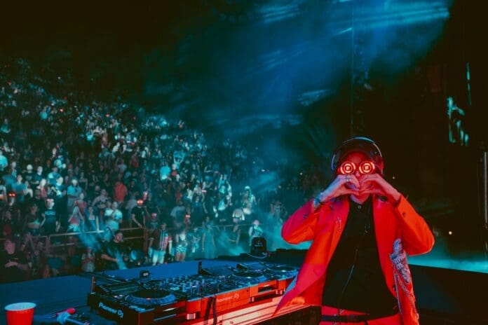 A DJ is standing in front of a crowd at REZZ Rocks V.