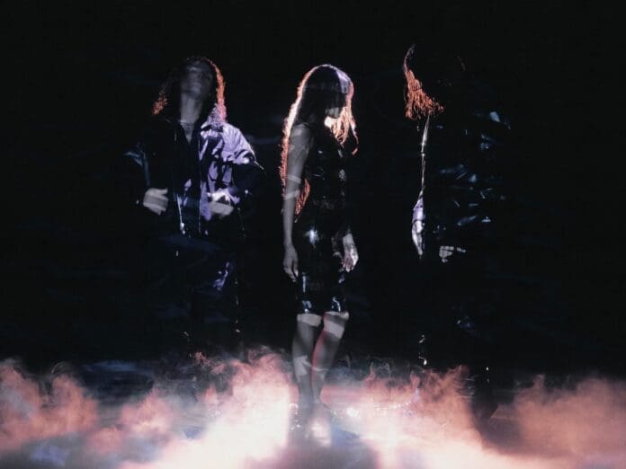 Three people standing in front of smoke in a dark room, featuring Chrome Hearts' Jesse Jo Stark.