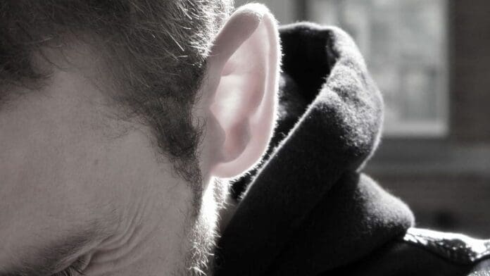 A man wearing a hoodie while producing and mixing music.