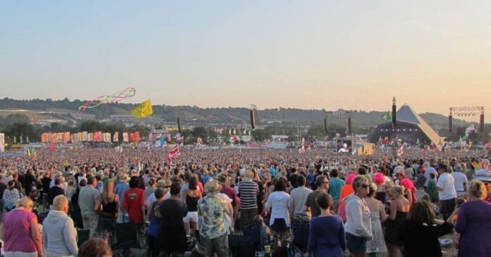 A large crowd of people at a music festival eagerly awaiting Glastonbury 2024 ticket sales.