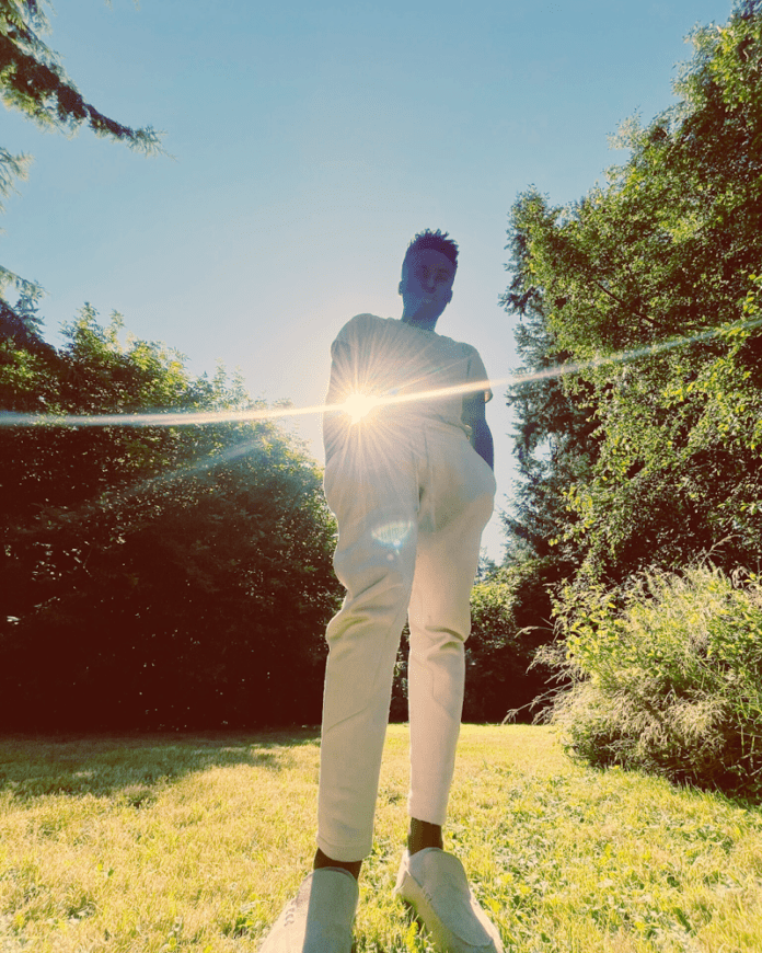 A man reminisces on a love lost to time in the grassy area illuminated by the sun.