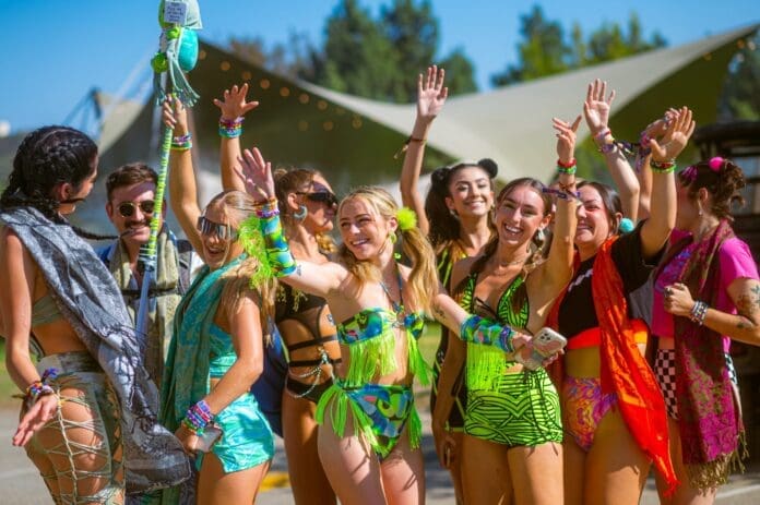 A group of people in colorful outfits posing for Five Fierce Looks at Nocturnal Wonderland 2023.