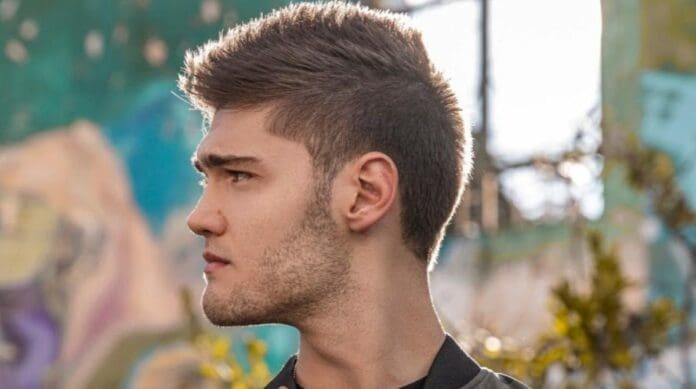 A young man is standing in front of a graffiti wall, Martin Trevy.