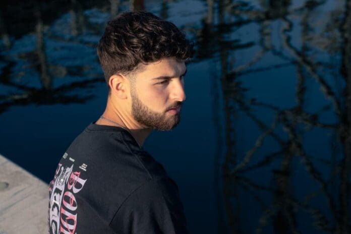 A man wearing a black t-shirt looking at the water, with 'TOKYO SZN' as the fourth track of his summer series.