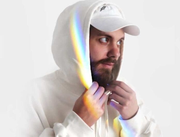 A man wearing a white hoodie with rainbow stripes attends San Holo's 'EXISTENTIAL DANCE MUSIC' album release party.