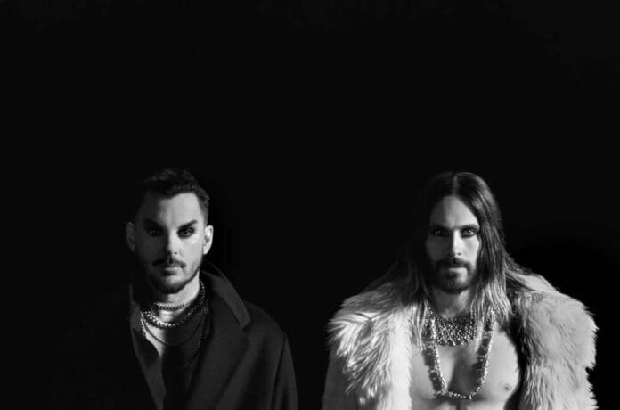 Two men in fur coats standing next to each other, featured in Thirty Seconds to Mars' 'It's the End of the World' Best New Music video.