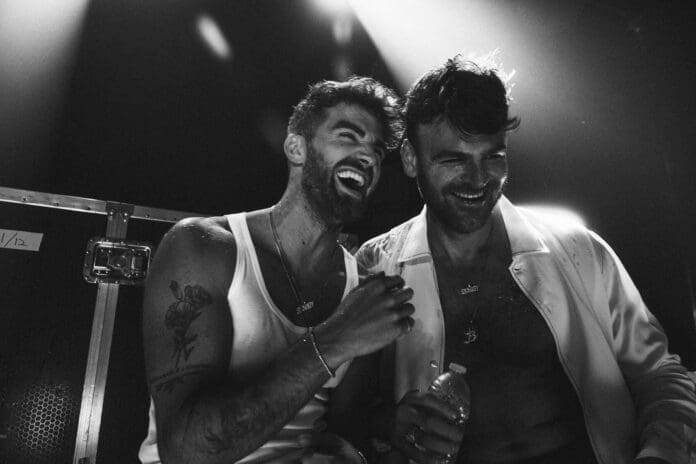 Two men at a concert enjoy a uplifting single by The Chainsmokers.