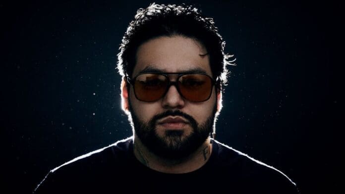 A bearded man with sunglasses in front of a dark background embodies the transformation from Deorro, a Prodigy on 'Panda Funk Radio,' to a global EDM icon.