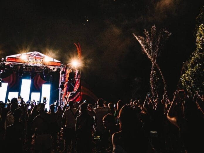 A crowd of people watching Sven Väth perform on stage at night.