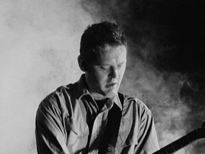 A black and white photo of a man playing an electric guitar, capturing the essence of this musician's artistry.