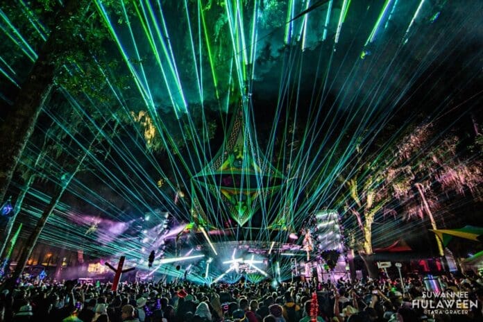 A crowd of people at a festival with green lasers at Suwannee Hulaween 2023.