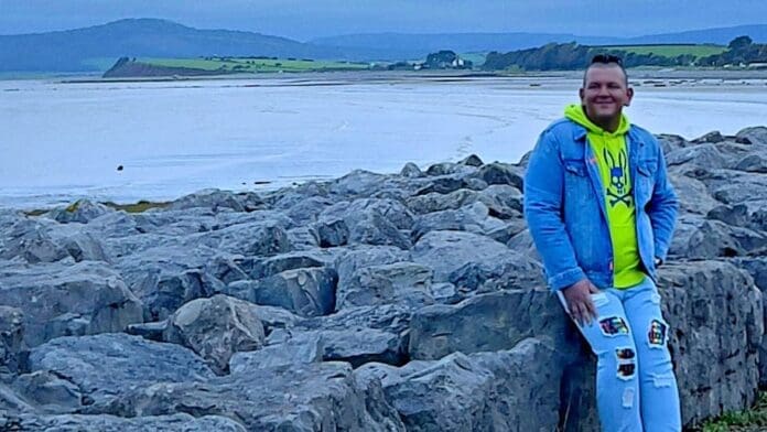 A man finds solace while leaning against rocks on a beach in 