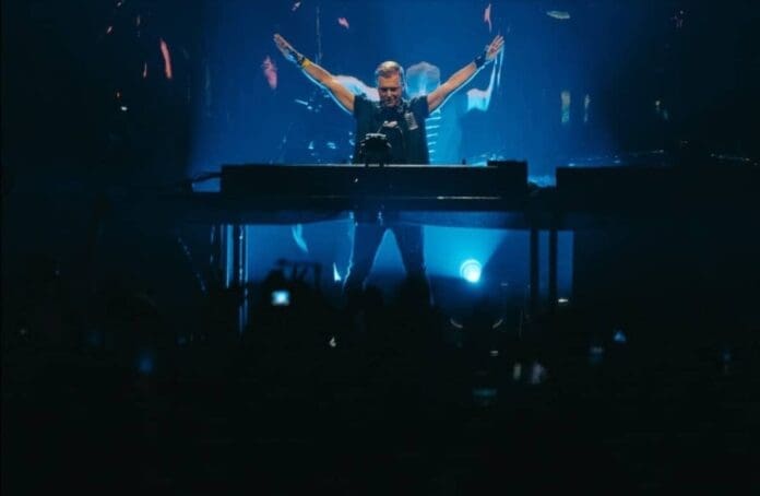 A man on stage with his arms outstretched at a State Of Trance concert in Rotterdam.