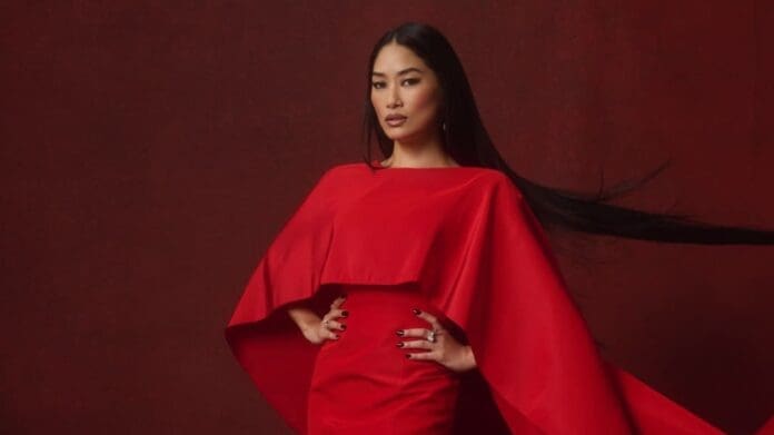 A woman posing on a red background.