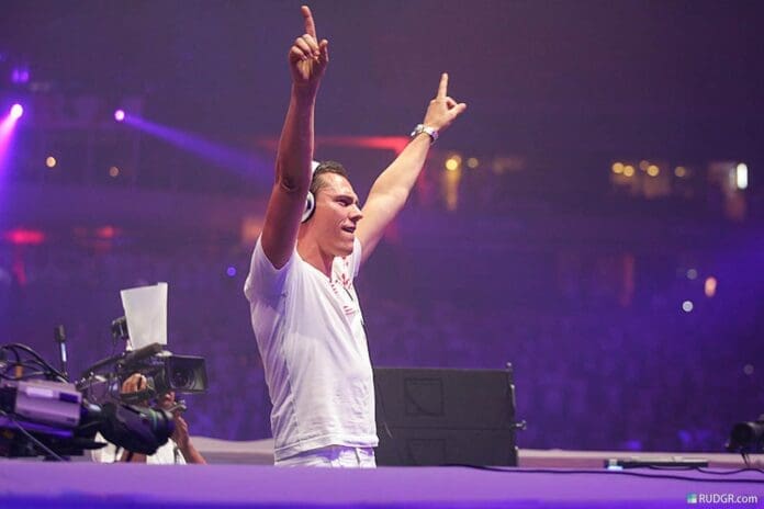 Tiësto, with his hands raised in the air, rules the world at a concert.