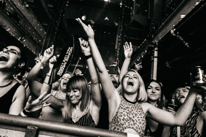 A group of people cheering at a concert during Defected Records New Year's Takeover.