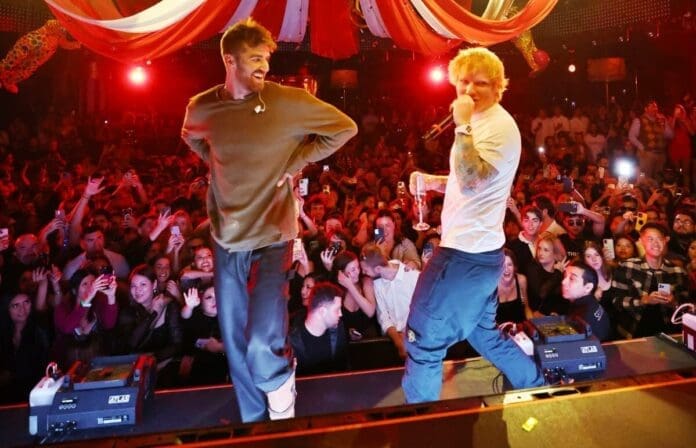 Two men, possibly The Chainsmokers or Ed Sheeran, standing on stage in front of a crowd at XS Nightclub.