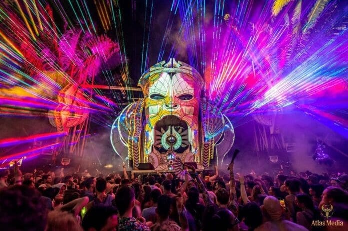 Envision Festival Announces 2024 Phase One Lineup, featuring a crowd of people at a festival with a large light show.