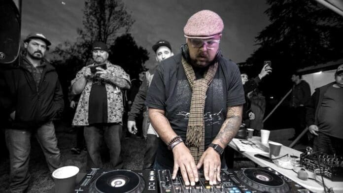 A bearded man playing a DJ set.