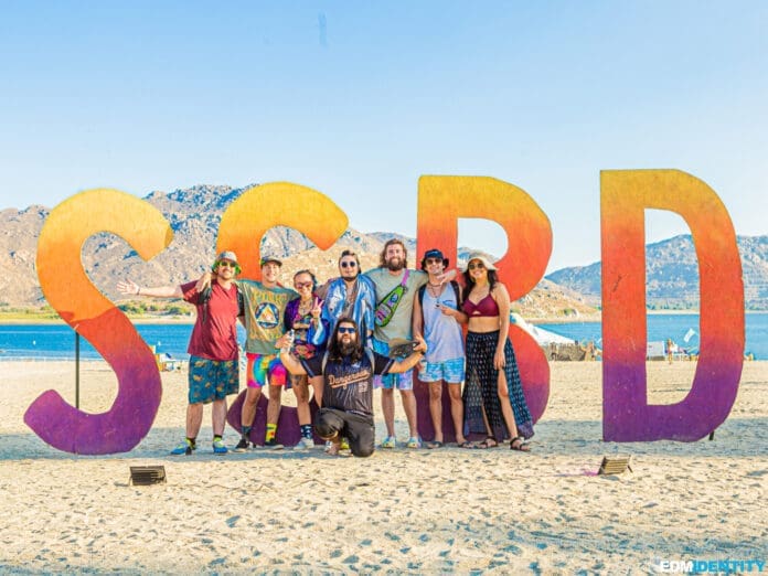 A group of people posing in front of a large sign, Same Shined.