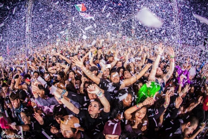 Insomniac Announces The Return Of Its Most Iconic NYE Event with a crowd of people waving confetti in the air.