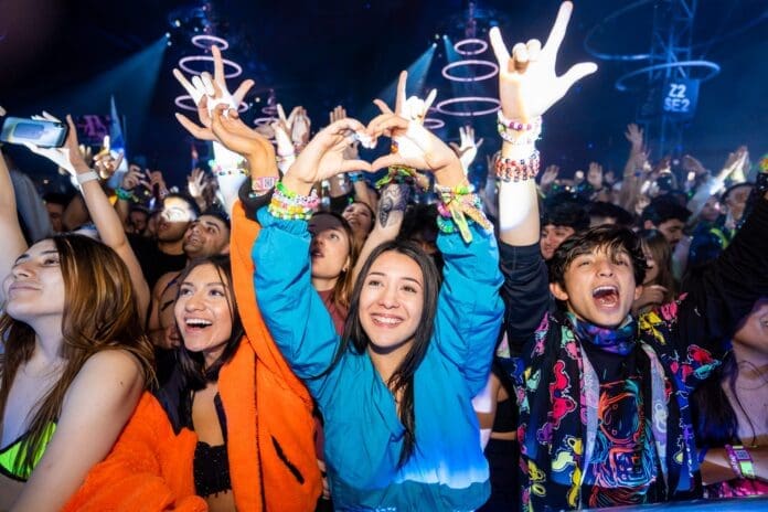 A lineup of people at a music festival, all with their hands up together.