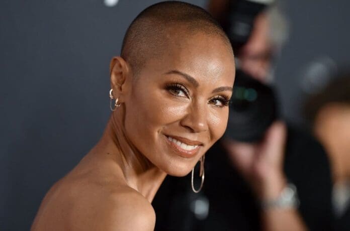 A woman with a shaved head smiles for the camera.