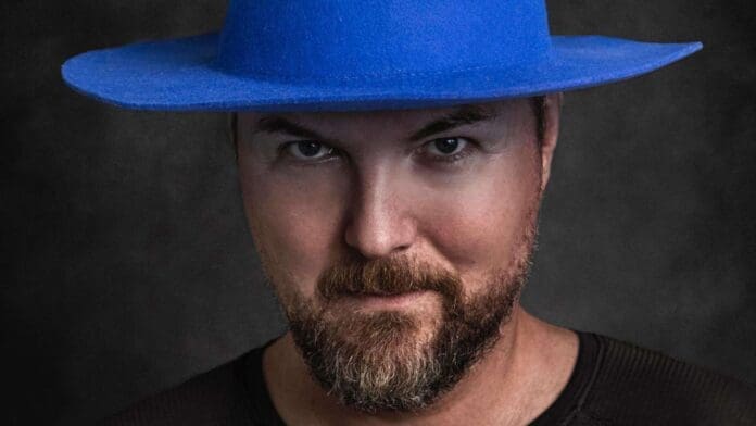 A man wearing a blue hat with a beard, passionately discussing his emotional new album 