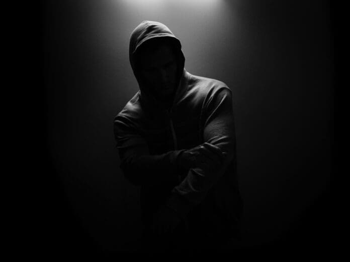 A man in a hoodie standing in the dark, listening to Kaskade's new track 'Save Me' from REDUX 006.