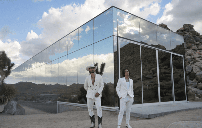 Two men in white suits standing in front of a glass building, revolutionizing Rock & Roll with 'Edge Of The Night'