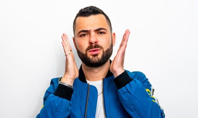 A man making a gesture with his hands in a blue jacket.