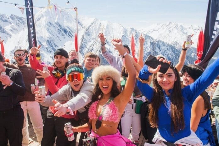 A group of people posing for a photo on top of a mountain during Austria's Snowbombing Festival.