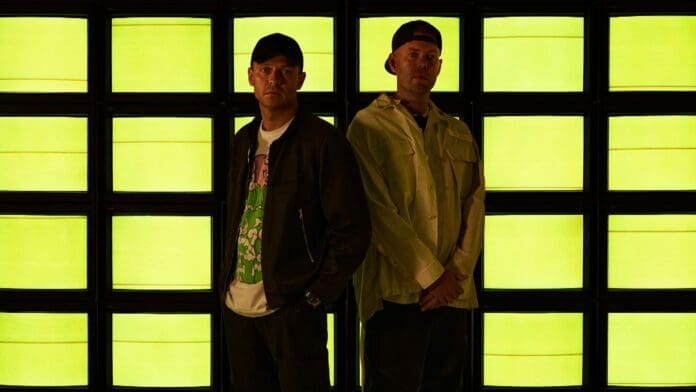 Two men standing in front of a yellow wall, as Solardo adds their distinctive flair to Something Good's 'Before Dawn' track.