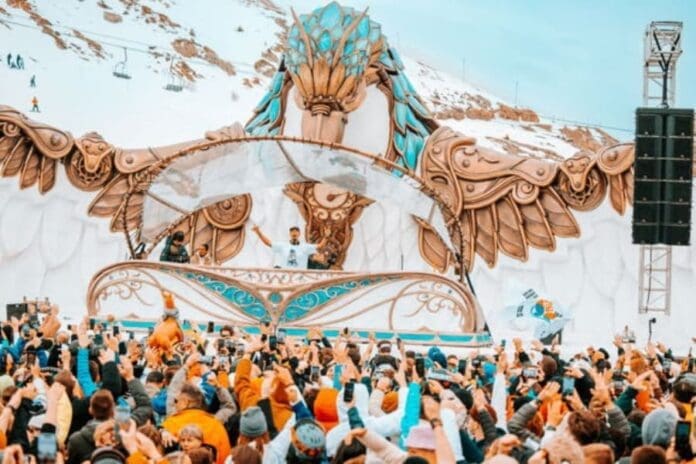 The 2024 Line-Up of Tomorrowland Winter features a talented group of people on a stage set against the majestic backdrop of a snowy mountain.