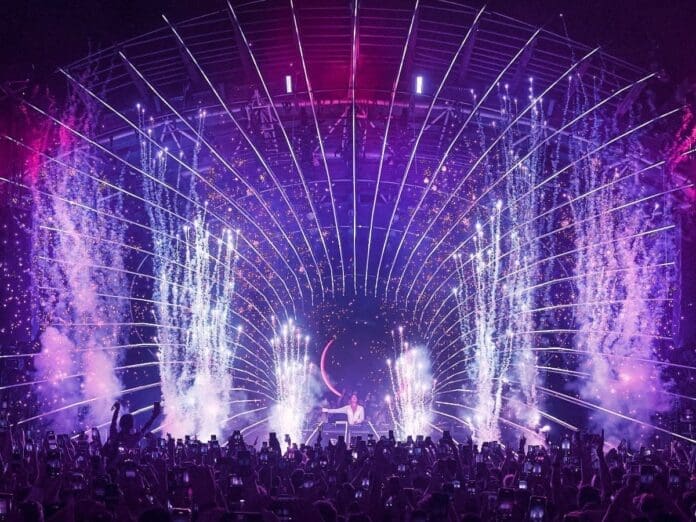 A crowd of people at the Ushuaïa closing party with fireworks in the background.