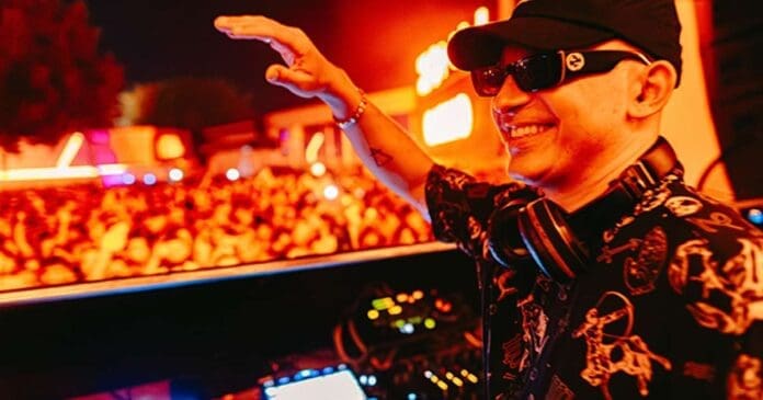 Watch a man in a hat and sunglasses djing in front of a crowd at DC-10, Ibiza.